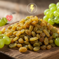 Raisins and green grapes on a wooden surface with health icons.